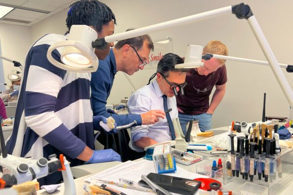 Dr. Javier Quiros shows a group of course attendees how to apply composite resin to a restoration case in his hands-on CE dental CE course.