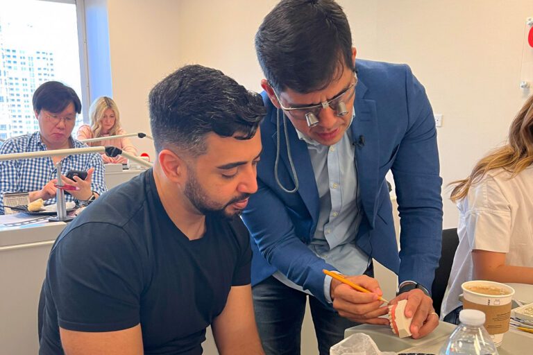 Dr. Klecio Alves guides a dental CE student on marking the tooth with a pencil for finishing and polishing at his composite restoration course.